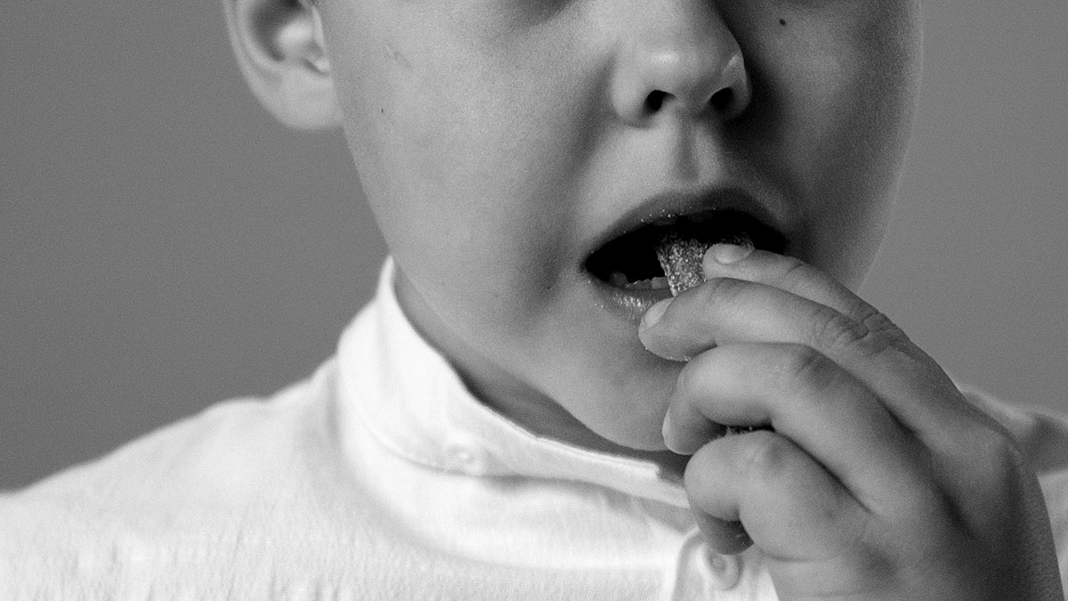 male child in white shirt eating candy