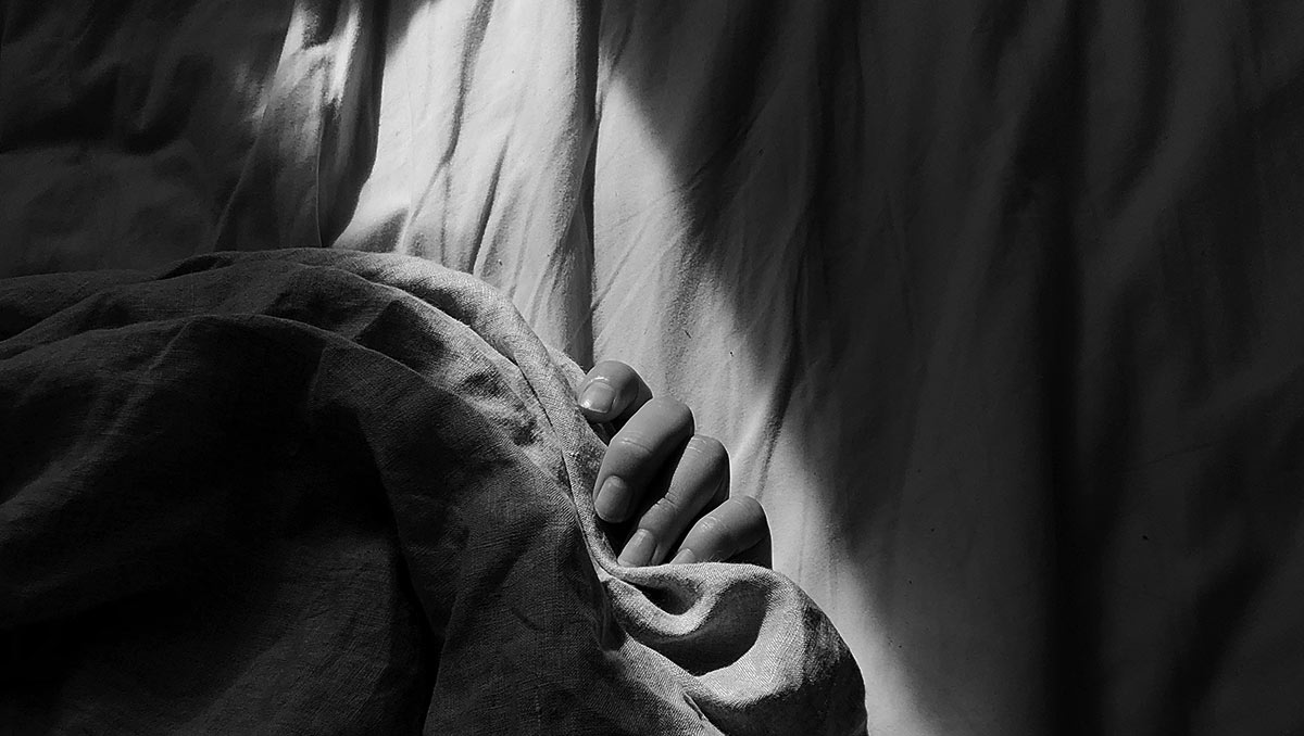 hand of person hiding under bedcovers